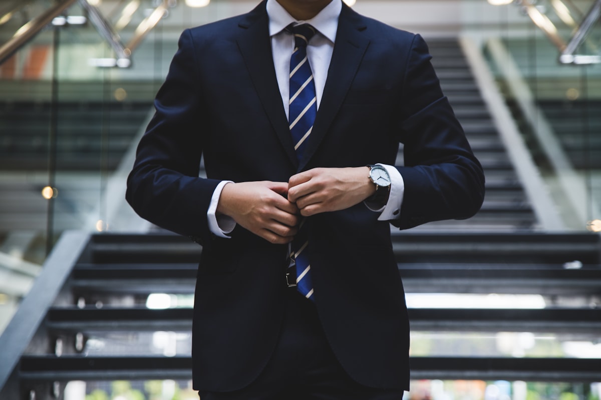 Master tailor conducting custom suit fitting with luxury fabric and measuring tape